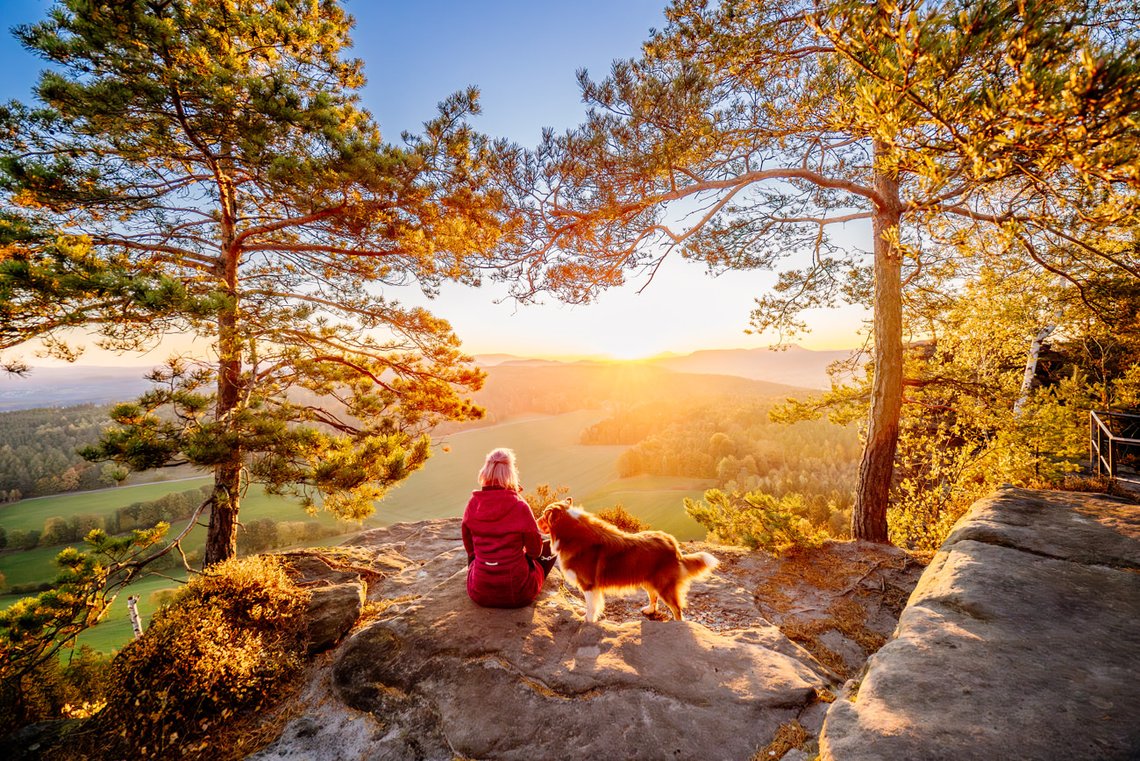 Hund und Frauchen auf dem Gipfel im Sonnenaufgang der Sächsischen Schweiz