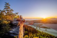 Dalmatiner und Frauchen auf einem Felsvorsprung bei Sonnenaufgang in der Sächsischen Schweiz