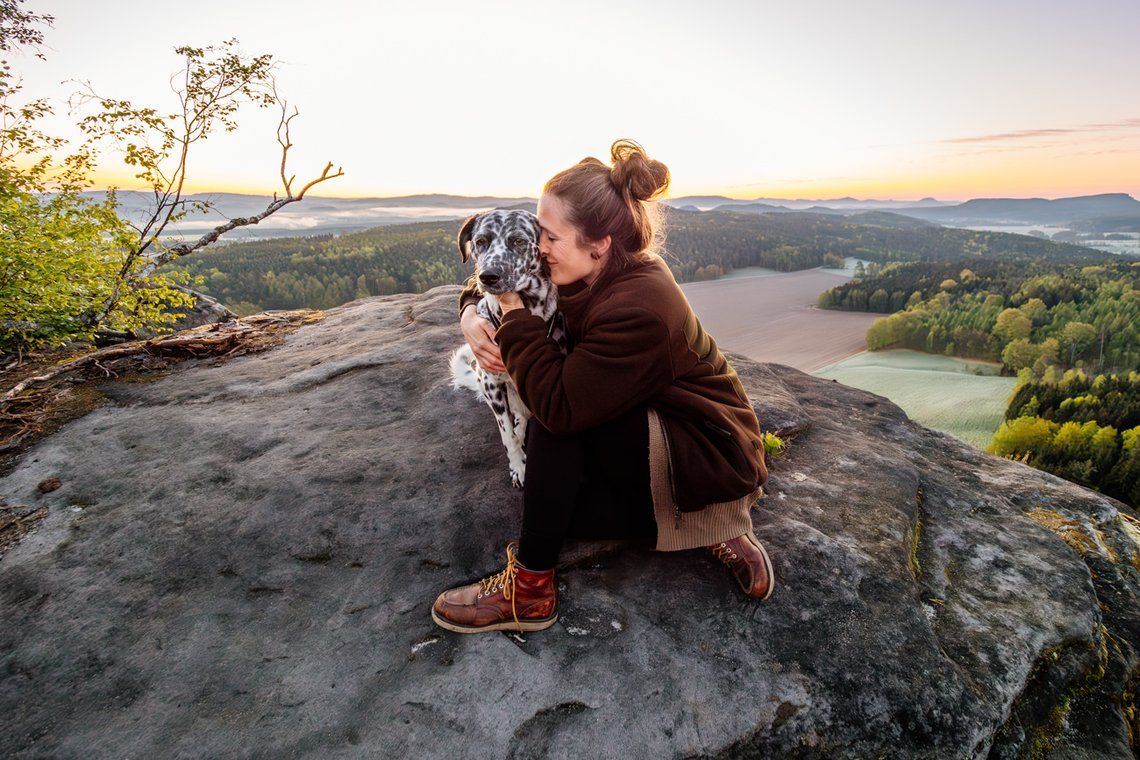 Dalmatiner und Frauchen kuscheln in der Morgendämmerung im Elbsandsteingebirge