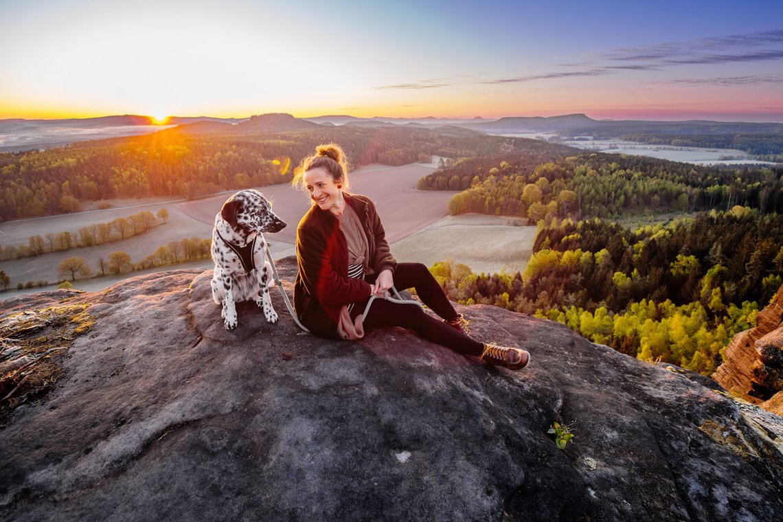 Dalmatiner und Frauchen auf dem Gipfel bei Sonnenaufgang im Elbsandsteingebirge