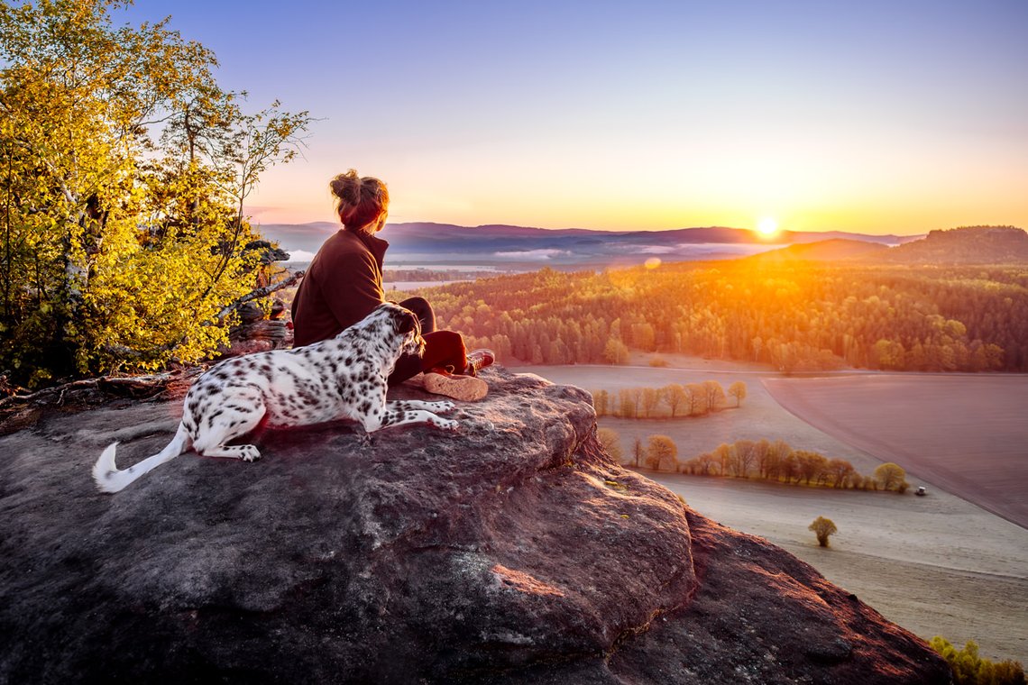 Dalmatiner und Frauchen auf dem Gipfel bei Sonnenaufgang im Elbsandsteingebirge