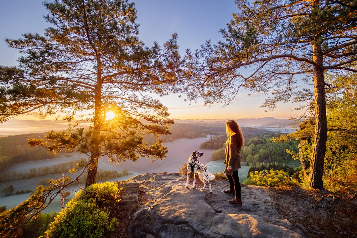 Episches Foto von Hündin und Frauchen bei Sonnenaufgang in den Bergen Sächsische Schweiz