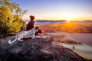 Dalmatiner und Frauchen auf dem Gipfel bei Sonnenaufgang im Elbsandsteingebirge
