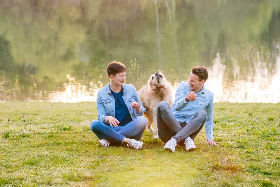 Golden Retriever schüttelt sich zwischen Frauchen und Herrchen am See