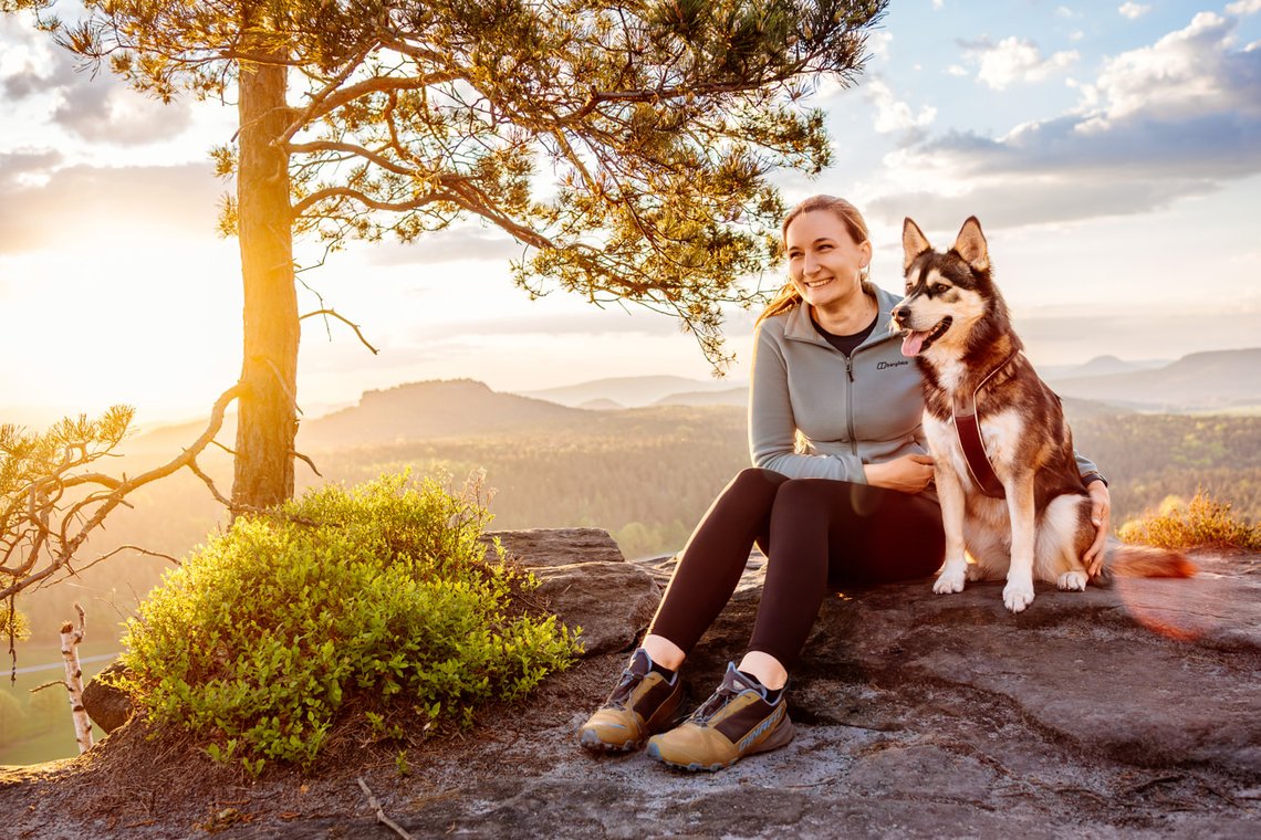 Hund und Halter im Sonnenaufgang in den Bergen