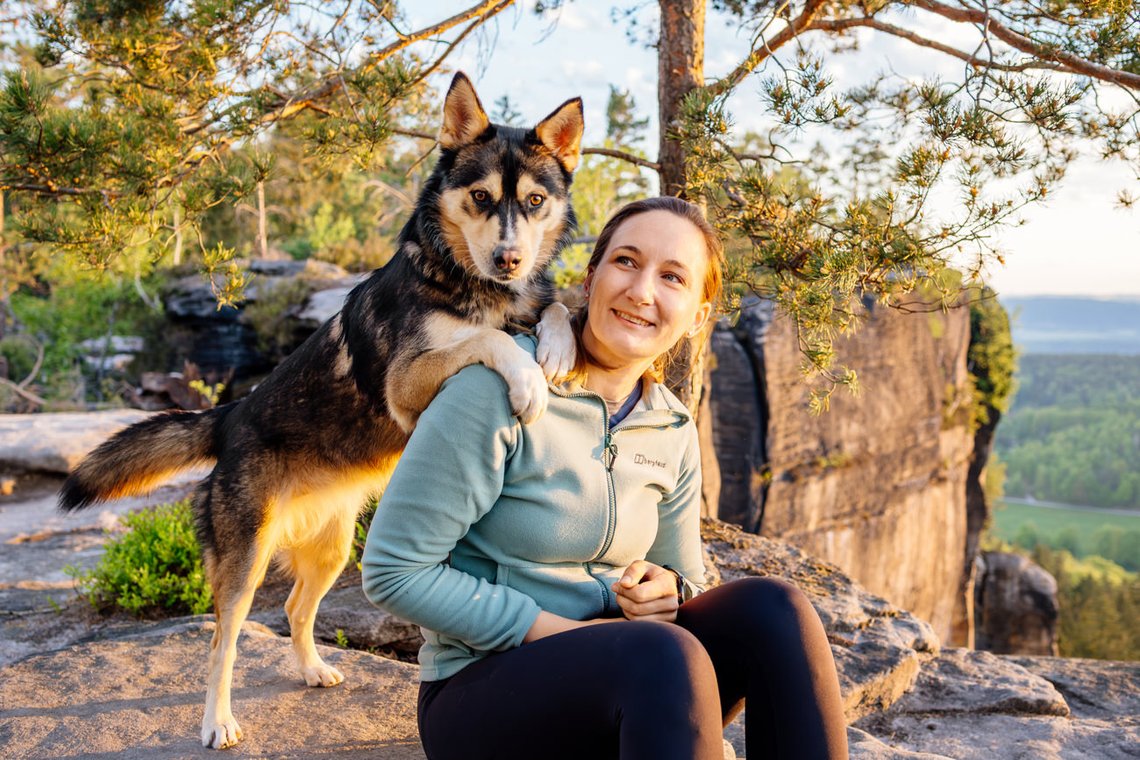 Huskymix steht auf den Schultern vom Frauchen