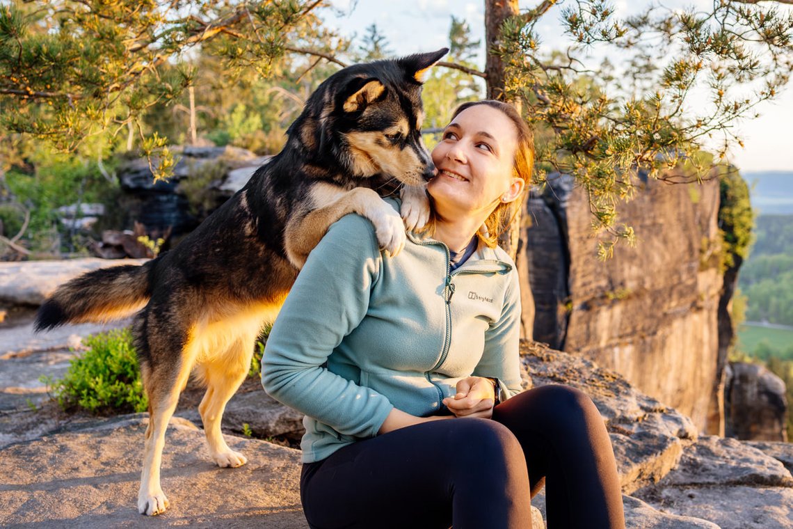 Huskymix steht auf den Schultern vom Frauchen